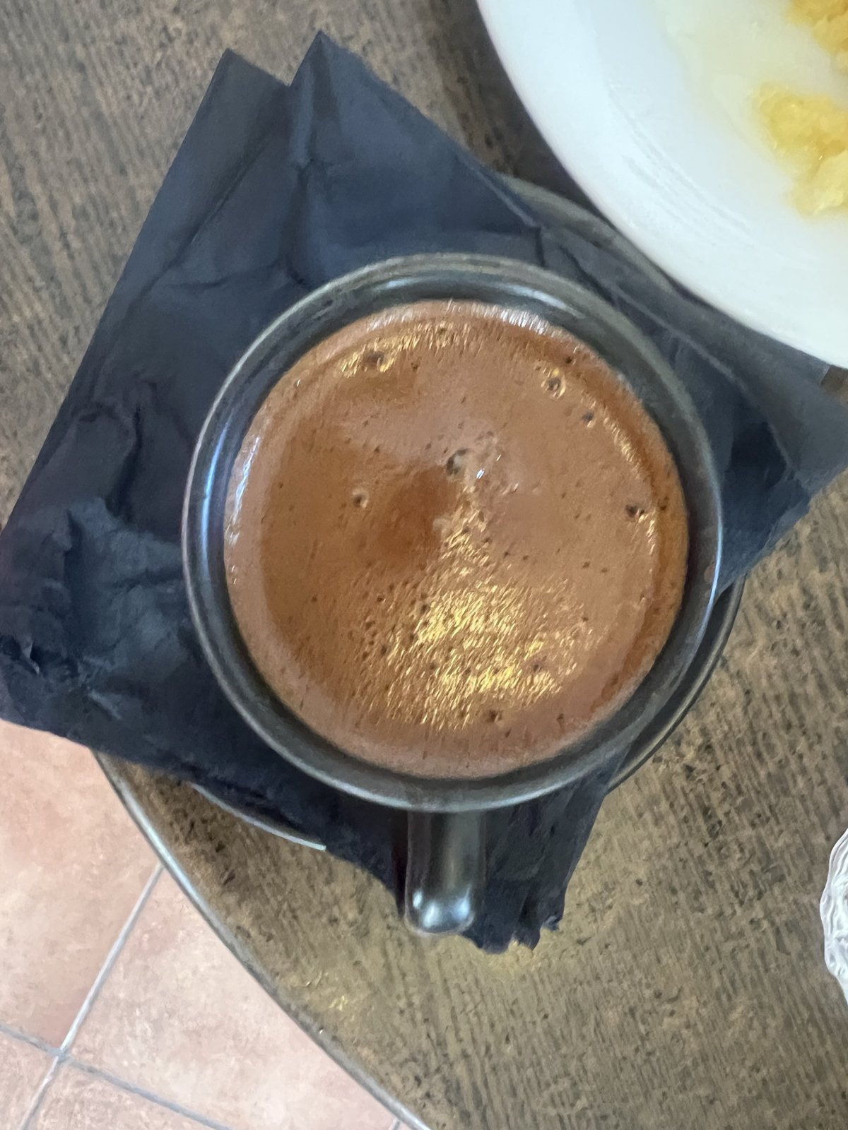 メスタ村のカフェ。黒い紙ナプキンの上に置かれた、泡の立ったギリシャコーヒーの小さなカップ